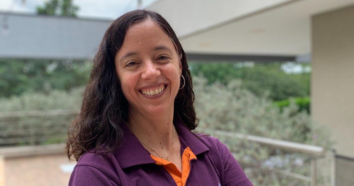Foto de Katia Lacerda, head de Pessoas e Cultura da Sensedia, sorrindo. Ela veste uma camisa polo roxa com detalhes em laranja e está em um ambiente externo com vegetação ao fundo. No texto, ela fala sobre jovens no mercado de trabalho
