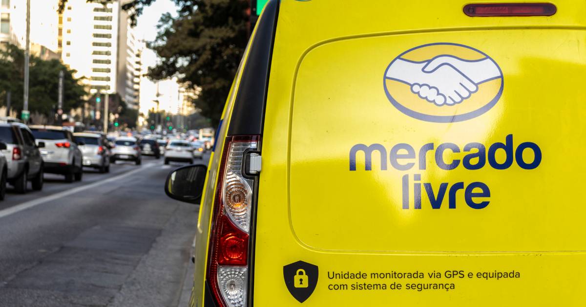 Veículo de entrega do Mercado Livre em destaque, com logotipo da empresa estampado na traseira amarela e informações de segurança sobre monitoramento via GPS, estacionado em uma avenida movimentada de grande cidade, marcas