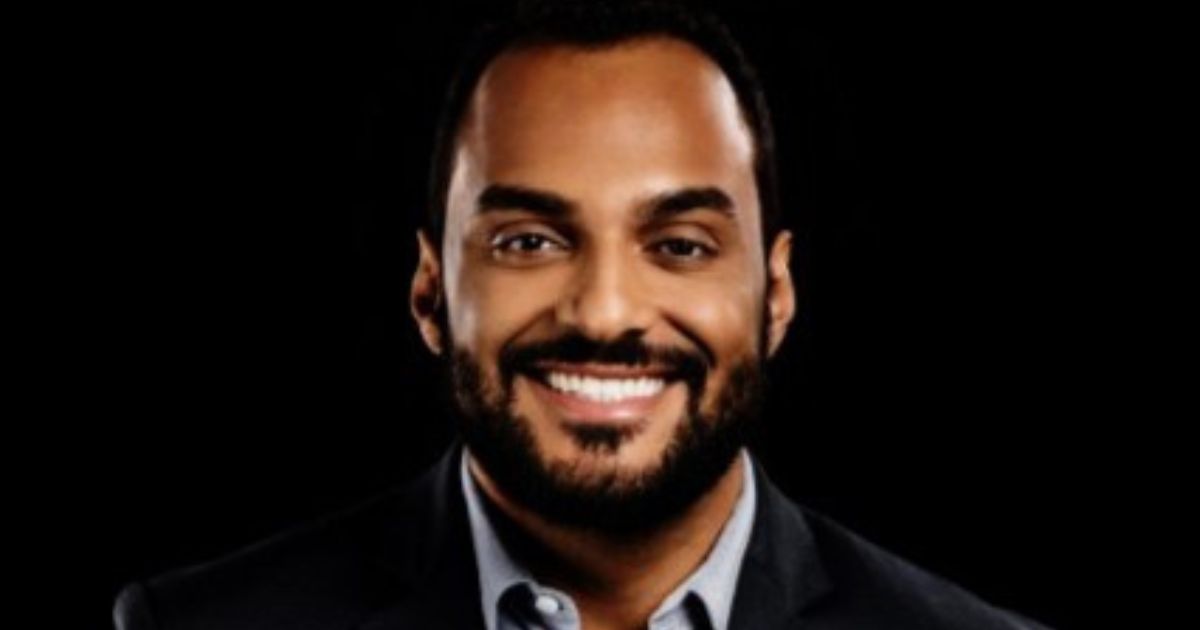 Marcelo Santos, então CIO global da Nexa Resources, em um retrato profissional. Ele sorri e veste um terno preto com camisa social cinza. O fundo da imagem é preto, destacando seu rosto e expressão amigável