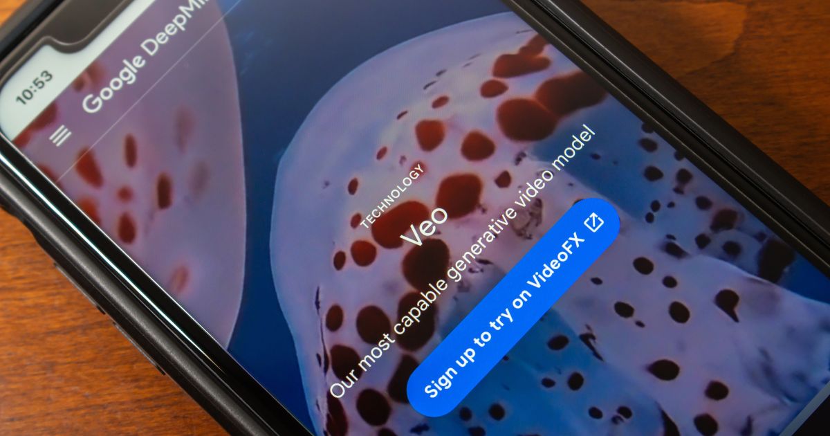 Ecrã de um smartphone a mostrar a página da tecnologia Veo, da Google DeepMind. A imagem de fundo exibe uma criatura marinha com manchas (possivelmente uma medusa ou polvo), e o texto em destaque diz “Our most capable generative video model” com um botão azul que convida o utilizador a inscrever-se para testar no VideoFX.