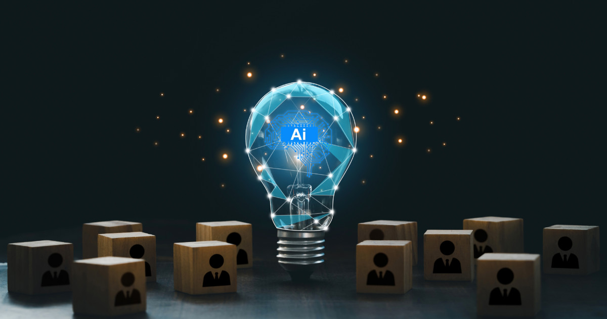 Imagem de uma lâmpada transparente iluminada, com um circuito digital e a sigla "AI" (inteligência artificial) no centro, representando inovação tecnológica. Ao redor da lâmpada, há blocos de madeira com ícones de pessoas em traje social, simbolizando o uso da inteligência artificial em contextos de negócios e gestão de pessoas. O fundo escuro destaca os elementos digitais brilhantes, sugerindo tecnologia e criatividade (médias e grandes empresas)