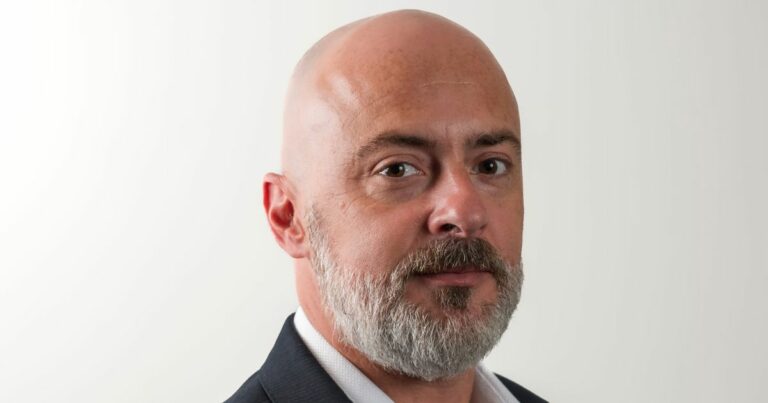 : Dirval Junior, diretor de vendas da Zadara Brasil, com expressão séria, vestindo terno escuro e camisa branca, em fundo branco neutro. Foto: Divulgação.